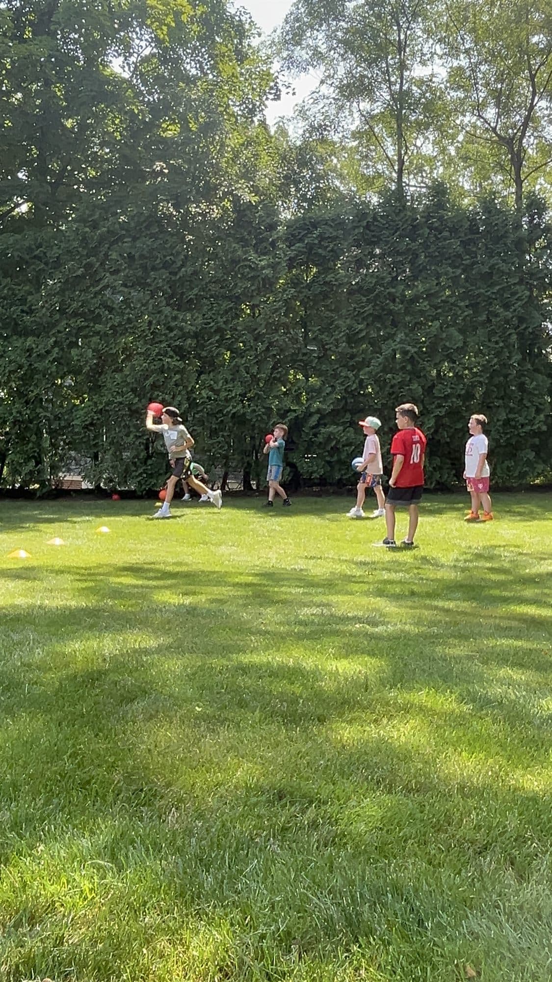 A camper takes a swing on the grass while a line of campers waits for a turn.