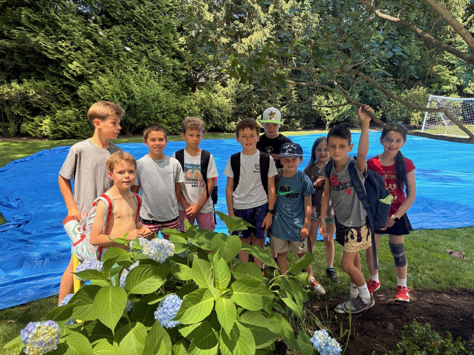 A group of campers posing together on the grass in front of a blue slip n slide.